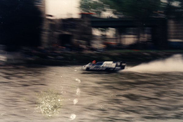 Bateau de course devant des bâtiments sombres, effet de mouvement prononcé.ᴬᴵ
