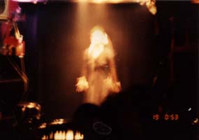 Femme en noire debout devant un micro sous les projecteurs.