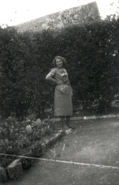 Femme debout en robe dans un jardin. Noir et blanc.