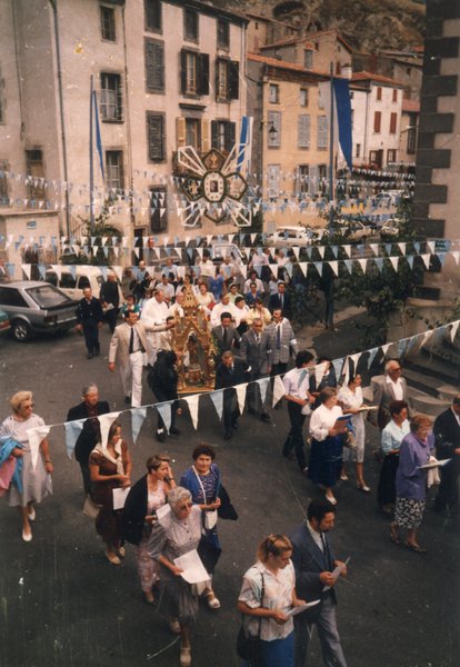 Procession religieuse dans une rue avec des femmes portant des partitions.