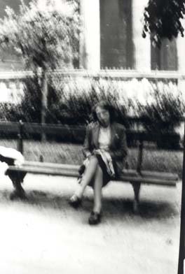 Jeune femme assise sur un banc dans la rue. Noir et blanc.