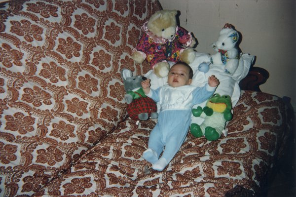 Bébé couché sur un canapé au milieu de peluches.