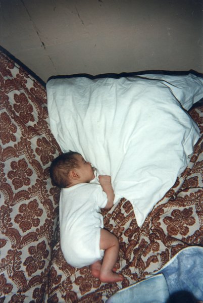 Bébé couché sur un canapé suçant un oreiller.