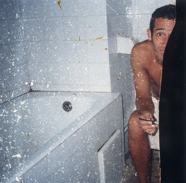 Homme assis  torse nu dans une salle de bain.
