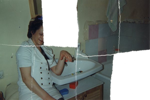 Femme brune assise dans une salle de bain. Image déchirée en partie reconstituée.