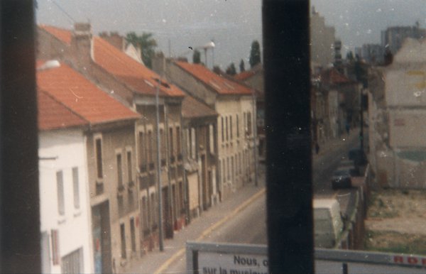 Rue et maisons alignées vues d’une fenêtre.